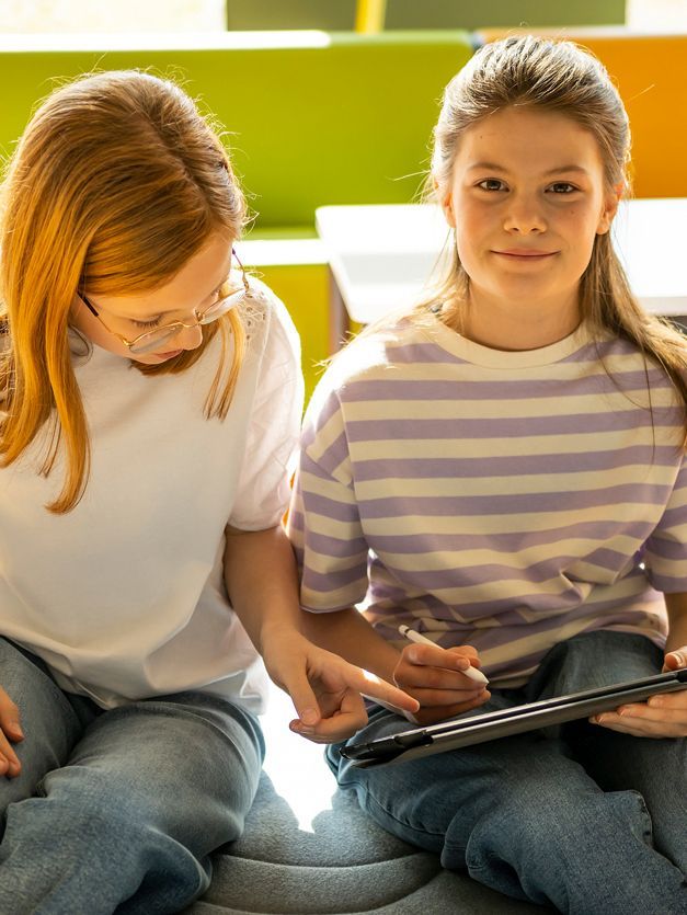 Two girls are interacting with a tablet
