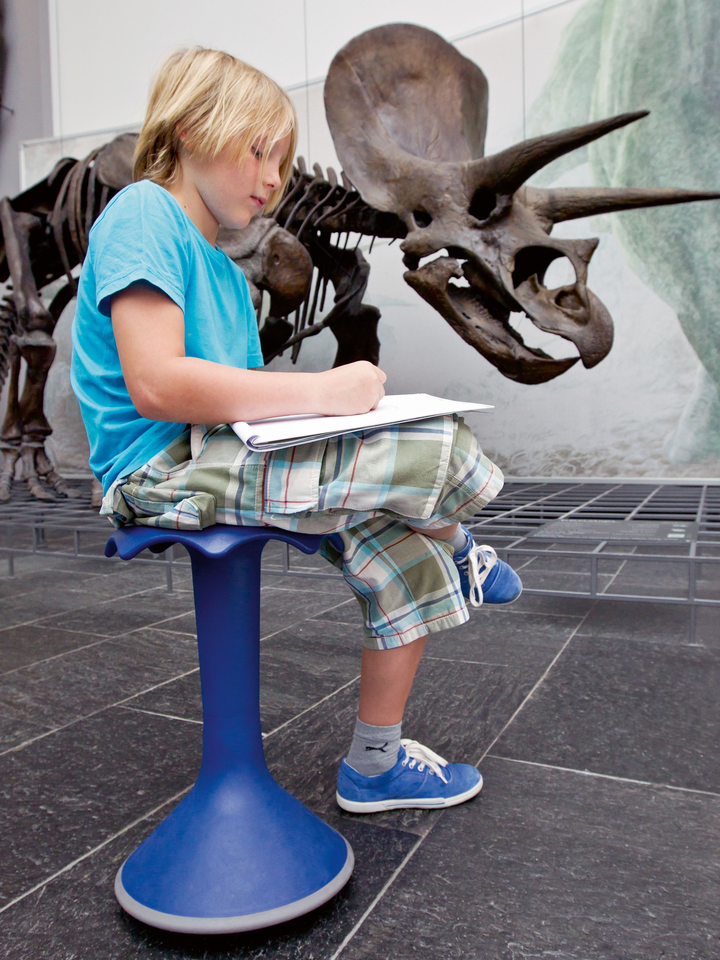 Ein Junge zeichnet auf einem blauen Hokki von VS im Senckenberg Naturmuseum in Frankfurt