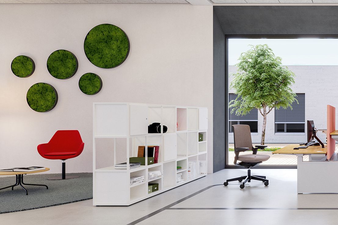 Le fauteuil rembourré Fan avec table d'appoint est séparé par une étagère basse de la table de bureau JustBe de VS.