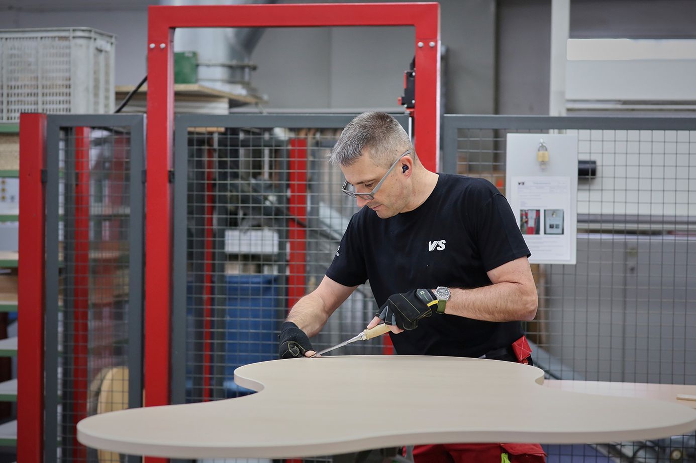 A wood technician works on a free-form table Puzzle in the manufacturing plant.
