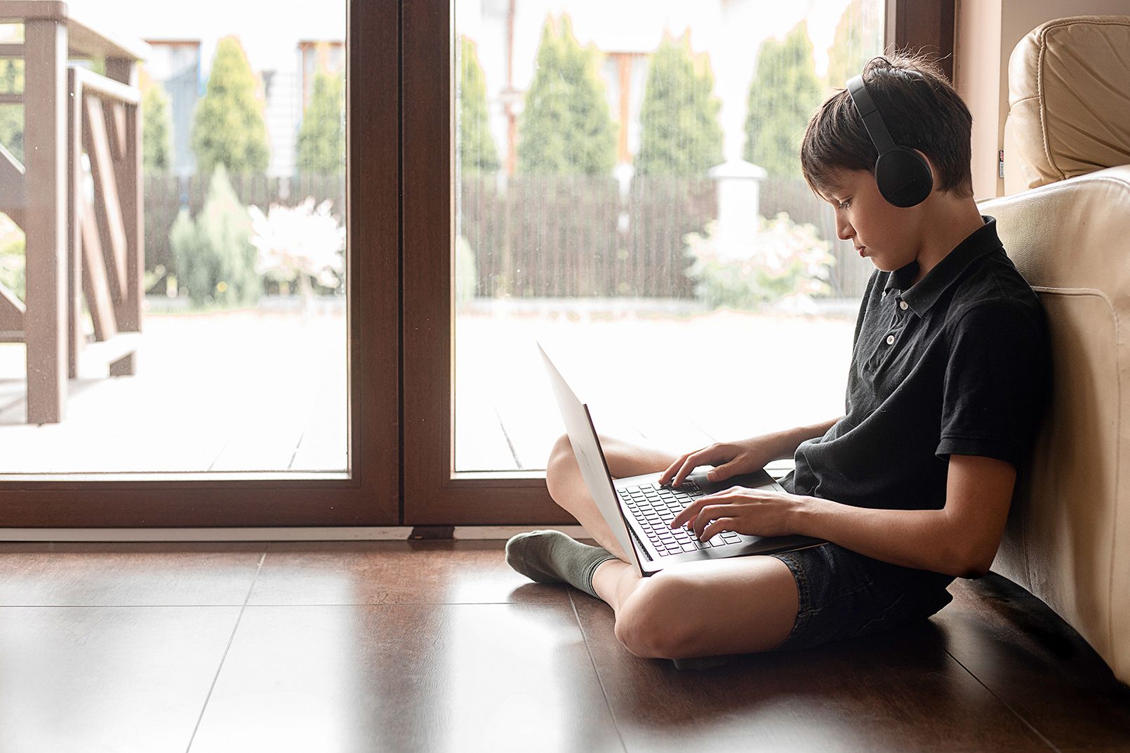 Junge mit Laptop sitzt am Boden