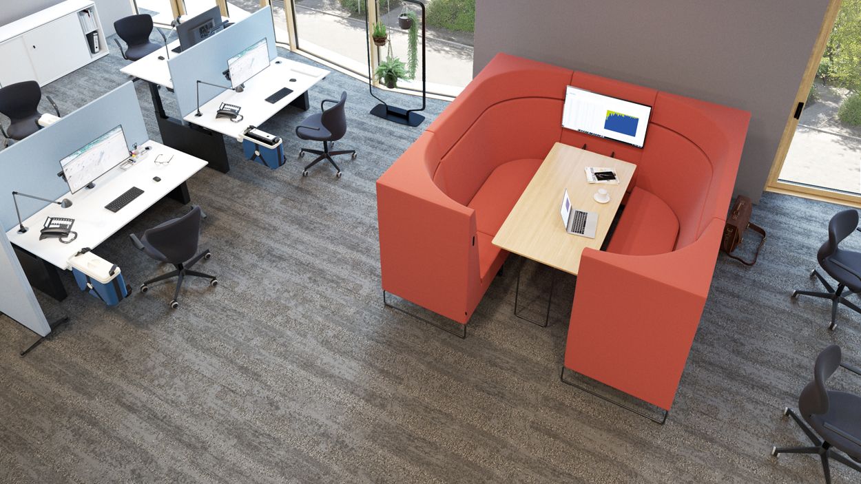 Work area with desks, black office chairs, and blue privacy panels; red seating area with a table and display for meetings.