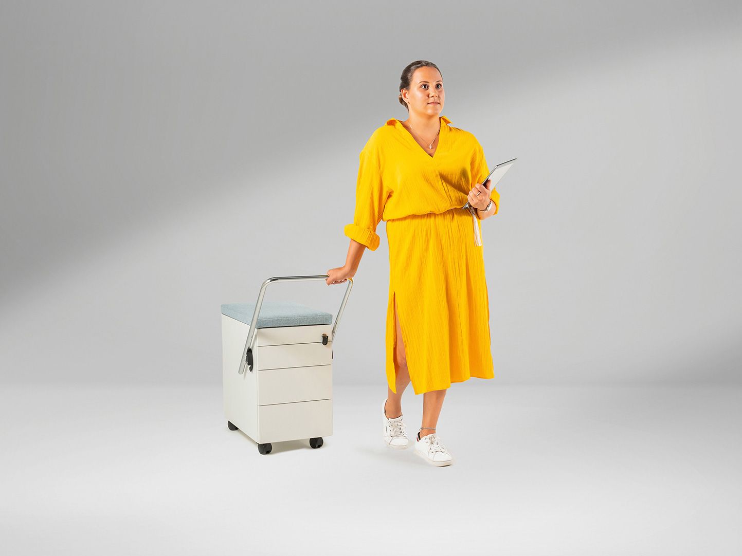 Junge Frau in gelbem Kleid zieht den Rollcontainer OfficeBox von VS hinter sich her.