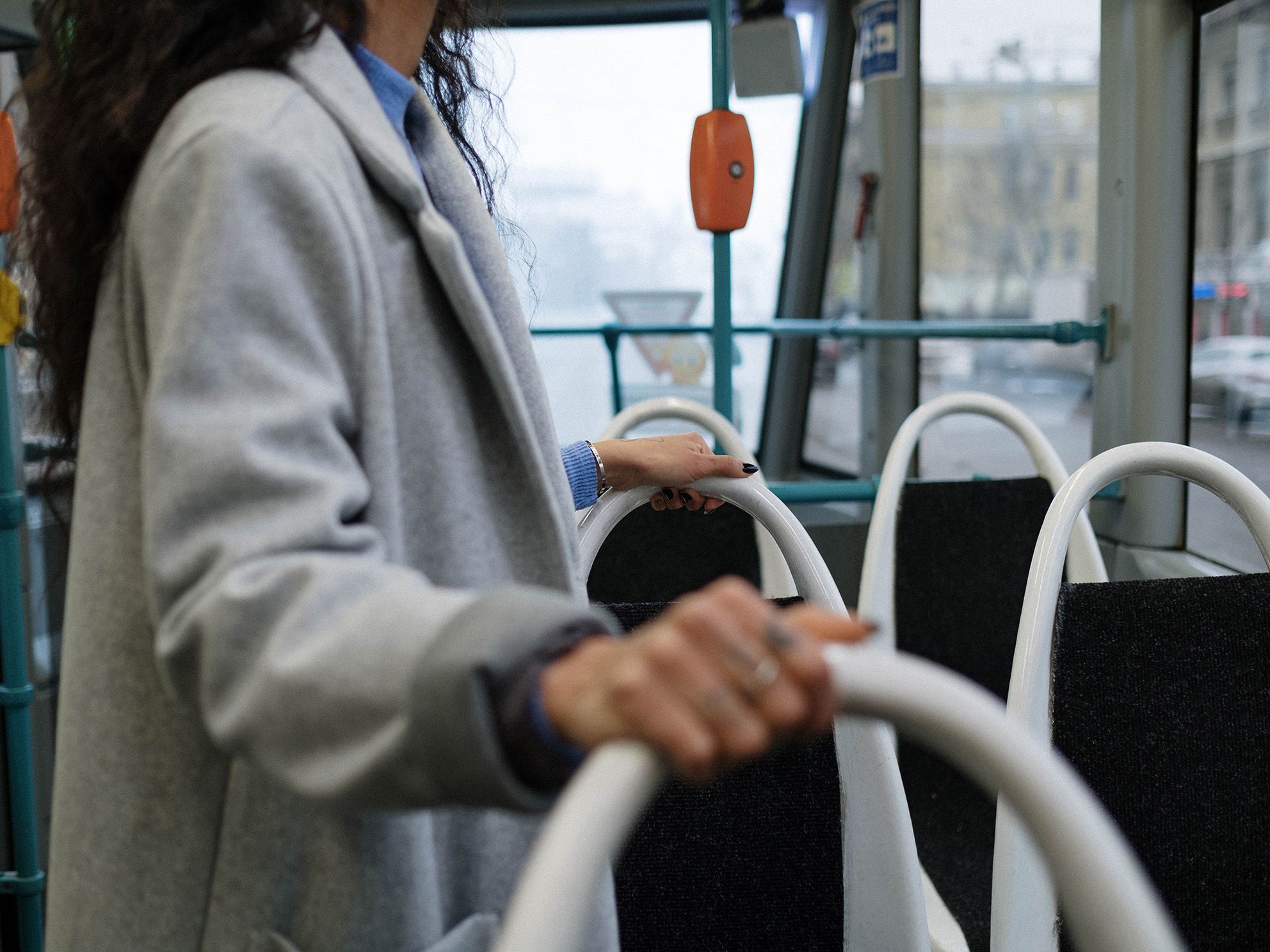 A woman holds on to handrails on a bus