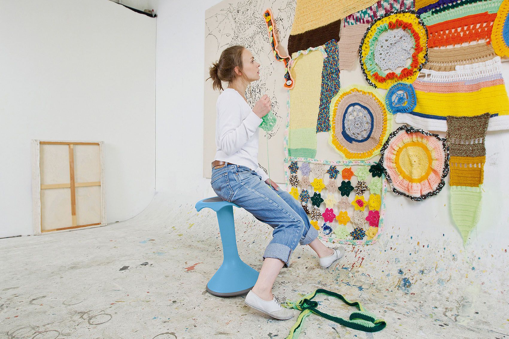 An artist sits on a light blue Hokki and creates a work of art