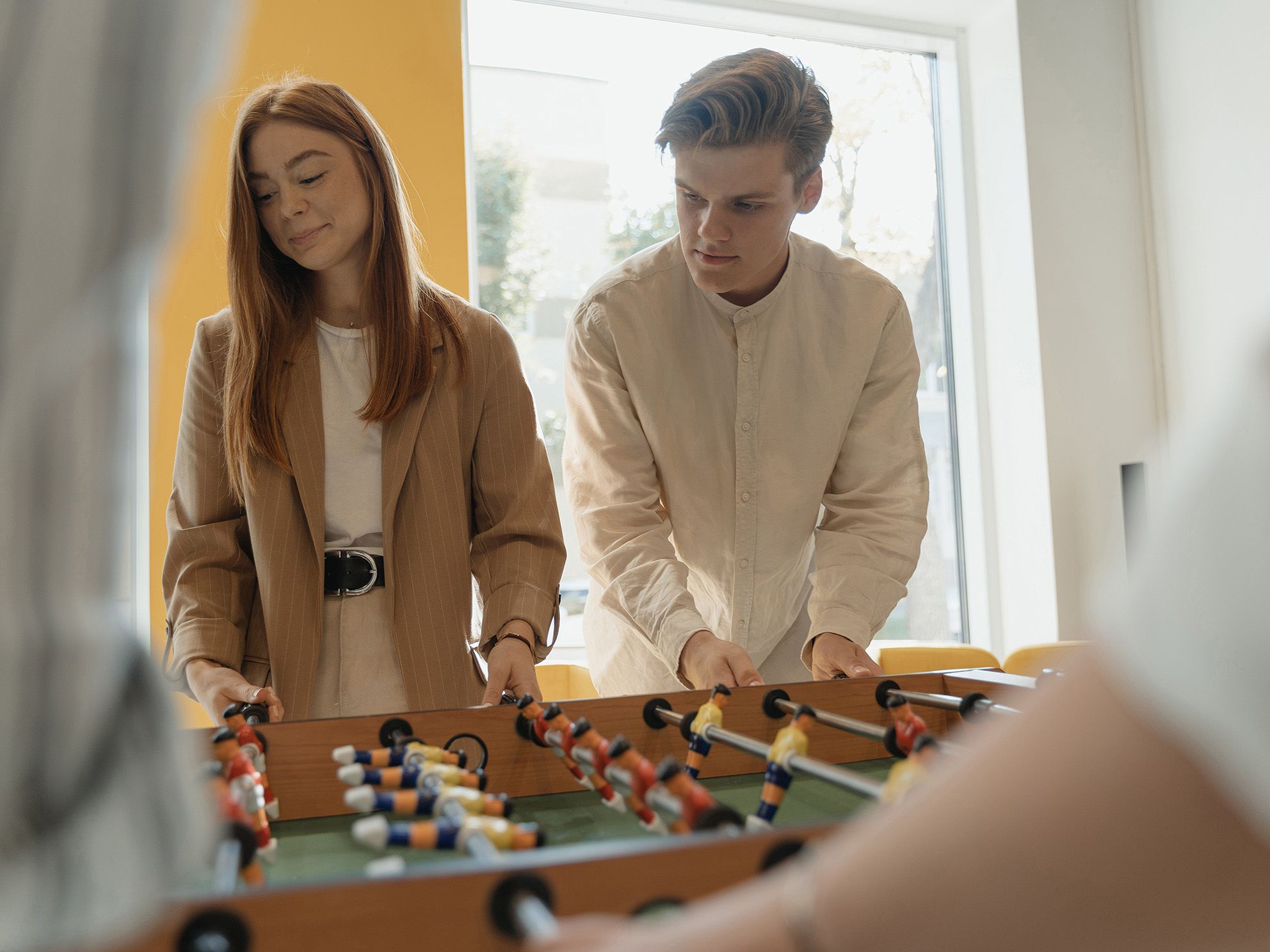 Two VS employees enjoy their break playing at a wooden football table.