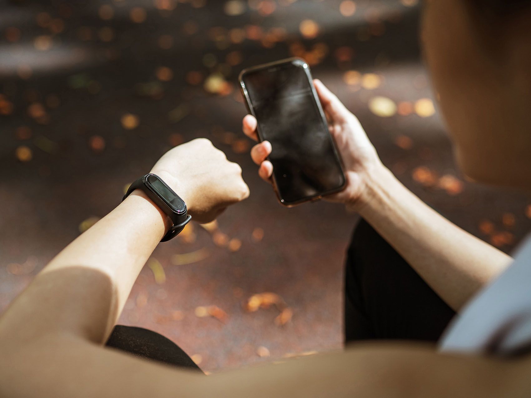 A man looks at his smartwatch and holds his mobile phone in his hand.
