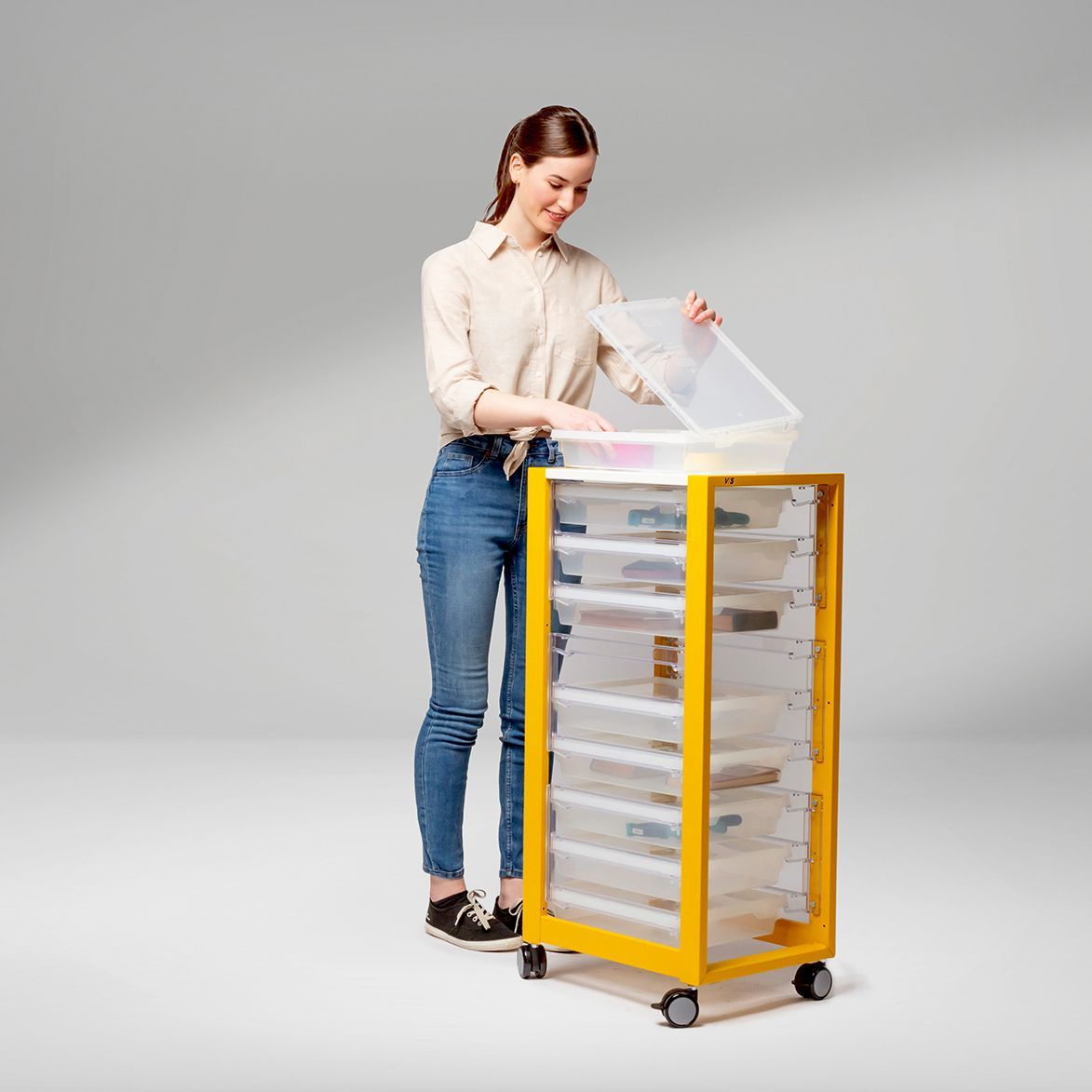Frau greift in einen entnehmbaren Schubkasten, der in einen mobilen Rollcontainer eingeschoben werden kann, um schnell und einfach Ordnung zu schaffen