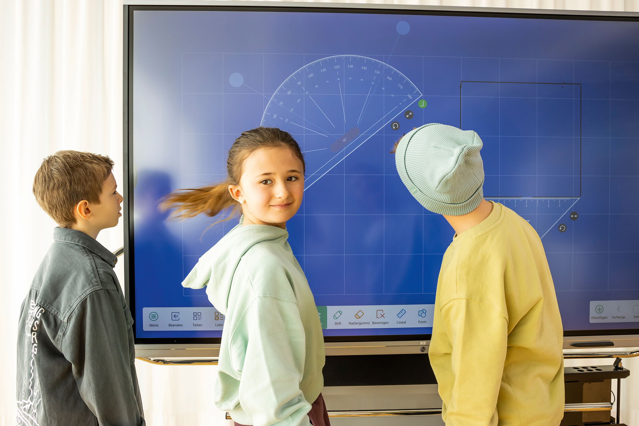 Three children draw geometric shapes on an interactive whiteboard by VS