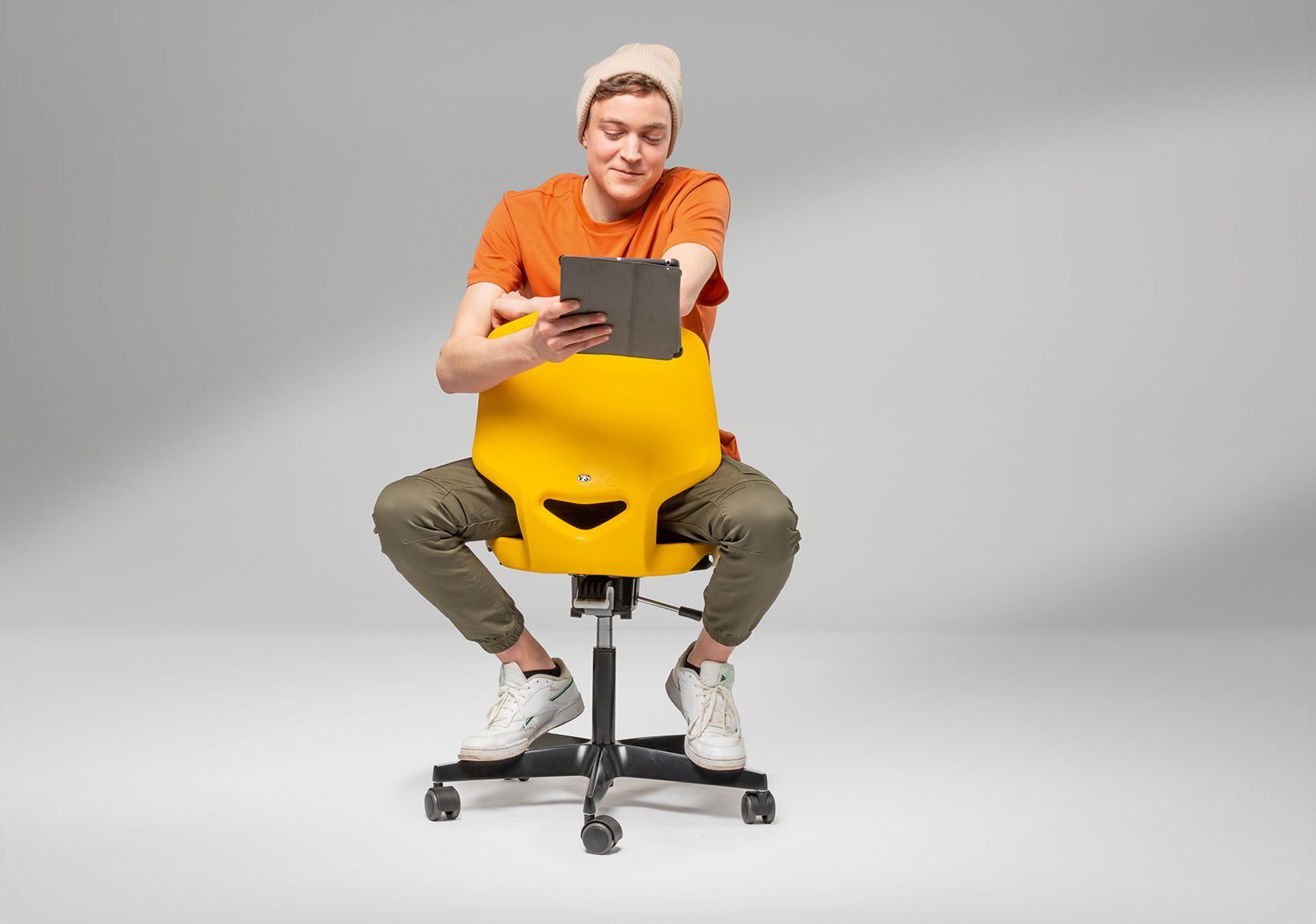 Ein Junge sitzt mit einem Tablet rittlings auf einem gelben Schülerstuhl JUMPER Air von VS.
