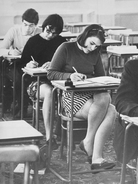 Black and white image of students at individual tables and chairs made of tubular steel