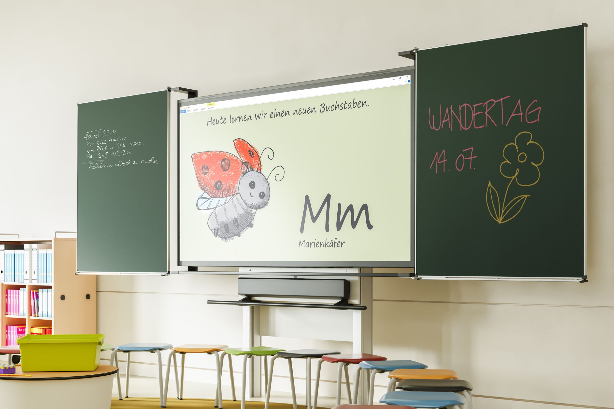 A VS-S-P3 display in an elementary school classroom, flanked by green blackboards, features a lesson on the letter M with an illustration of a ladybug. In front of it are colorful VS Rondo stools.