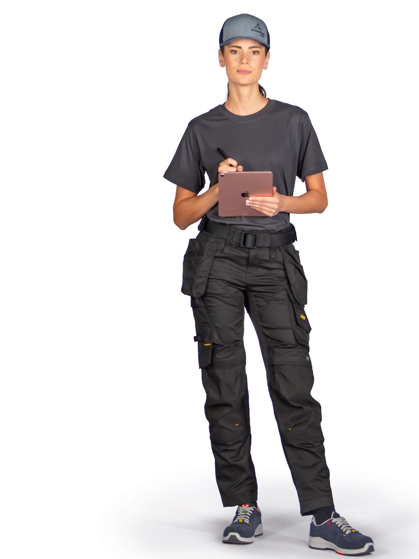 A woman in work clothes takes notes on a tablet—staying connected digitally and on the go in the trades.