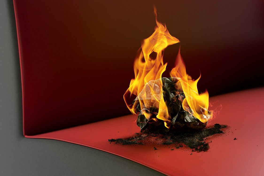 Ein brennendes Stück Papier auf einem VS-Sessel beim Papierkissentest für ausreichenden Brandschutz