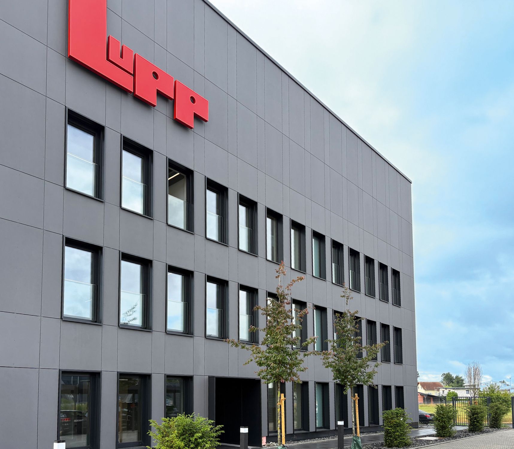 Exterior view of the new Lupp office building in Nidda, featuring a gray facade and a red company logo