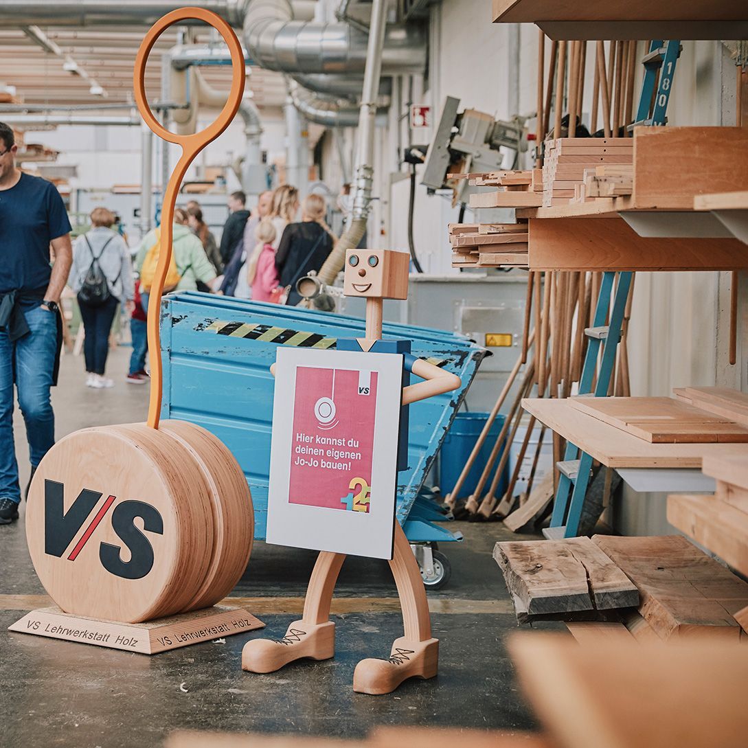 A wooden figurine invites visitors of the VS Open Day to build a yo-yo in the training workshop