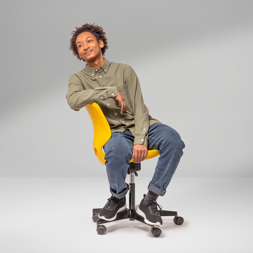 A young man sits sideways on a yellow JUMPER Air swivel chair by VS