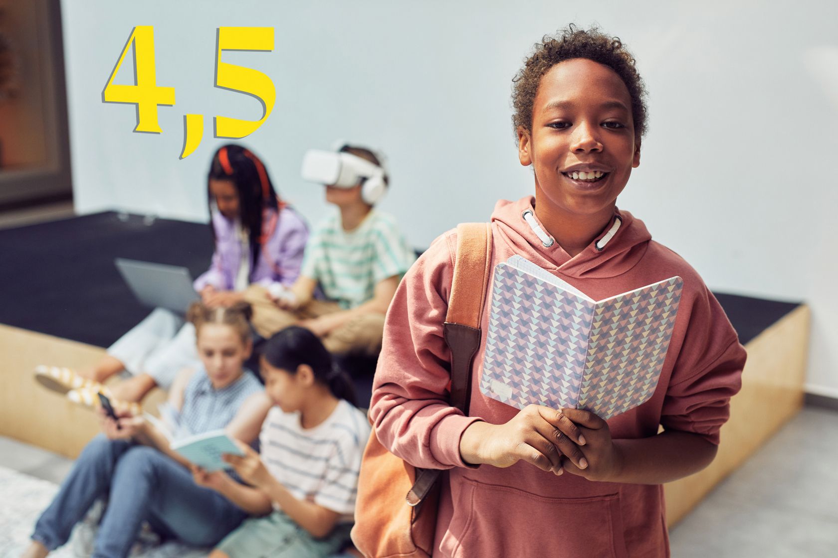 Black girl wearing pink hoodies and holding open notebooks, with four other children sitting in the background.